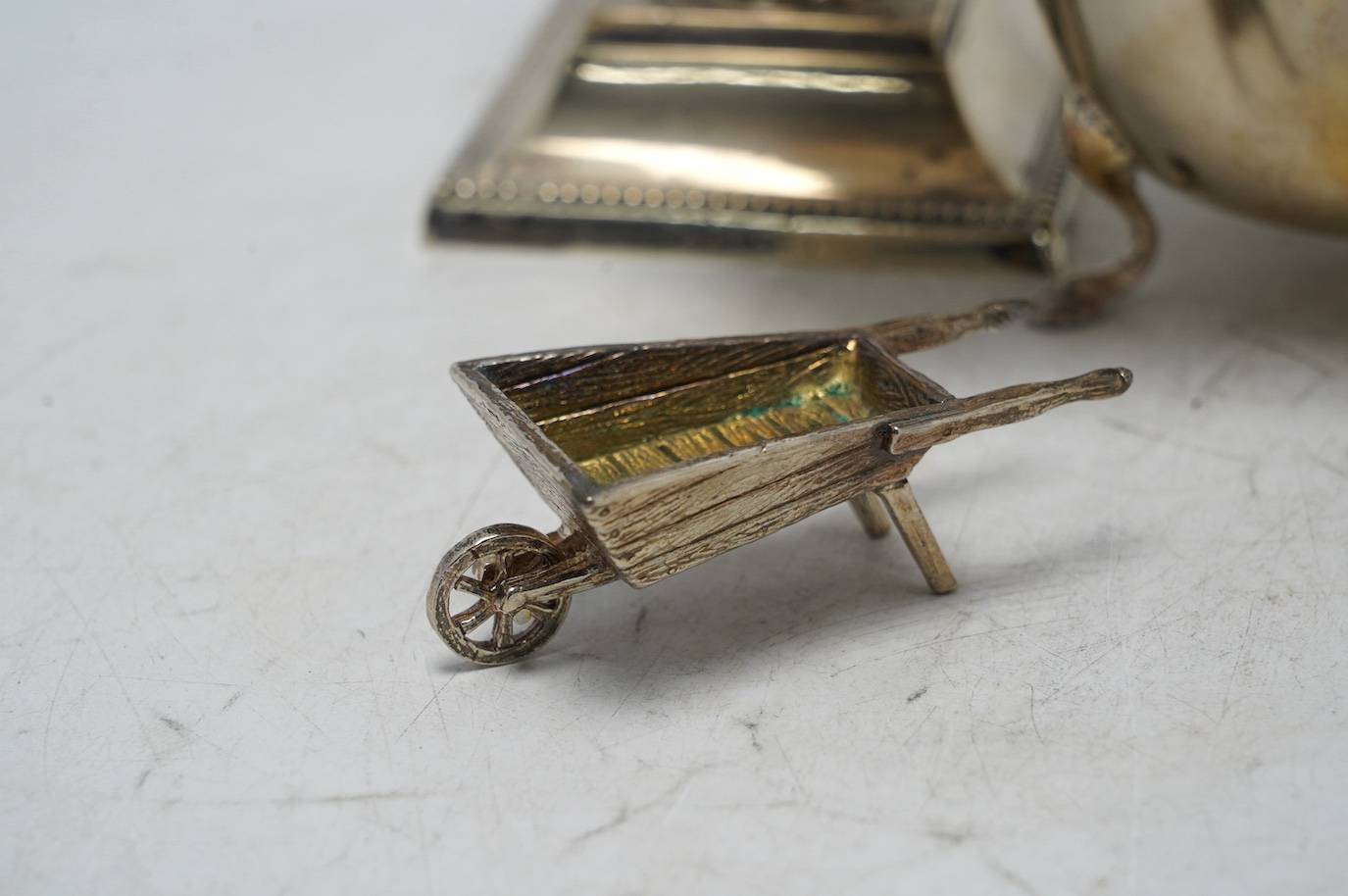 A late Victorian silver dwarf candlestick by Edward Hutton, London, 1893, 12.8cm, a silver sauceboat and three other items. Condition - fair